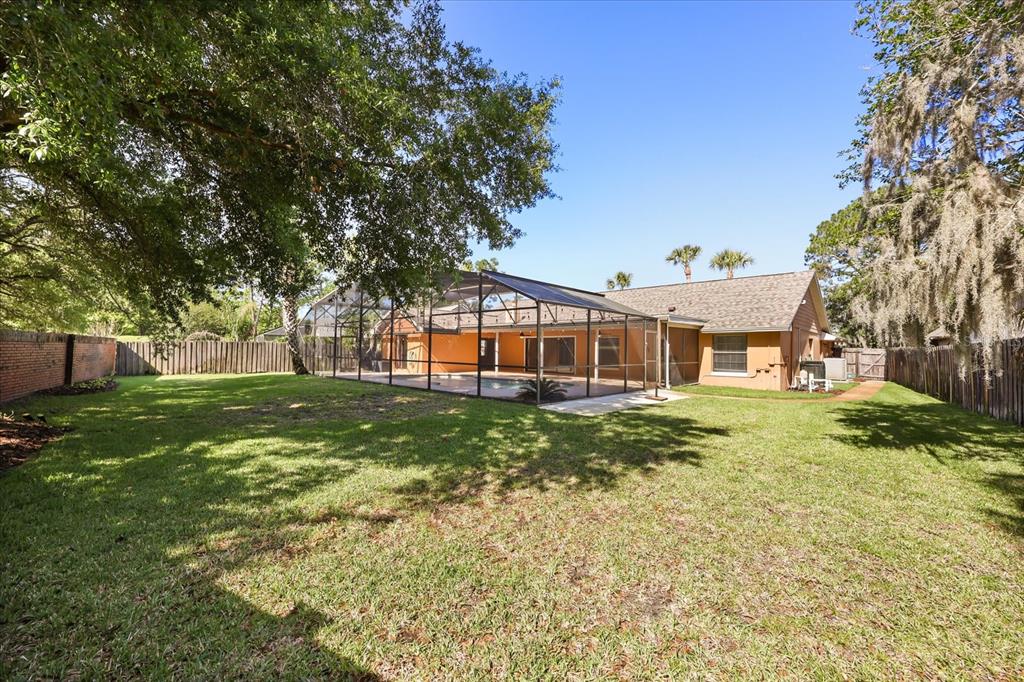 A backyard features a screened-in pool enclosure attached to the rear of a single-story house — 478 SABAL TRAIL CIRCLE, LONGWOOD, FL