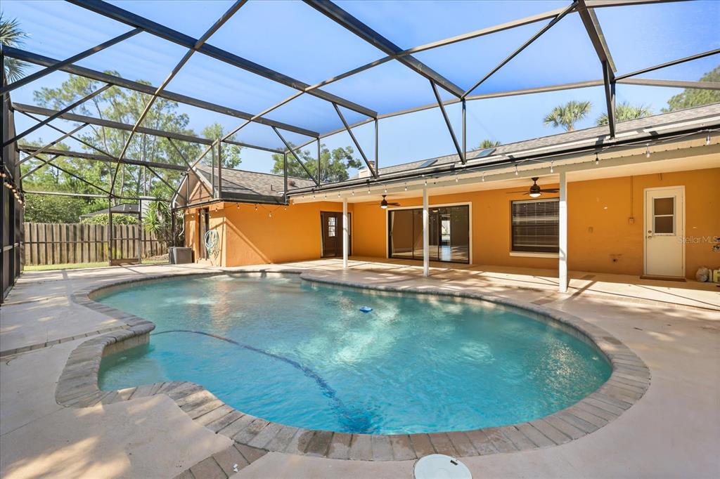 A swimming pool with a brick border sits inside a screened-in patio area — 478 SABAL TRAIL CIRCLE, LONGWOOD, FL