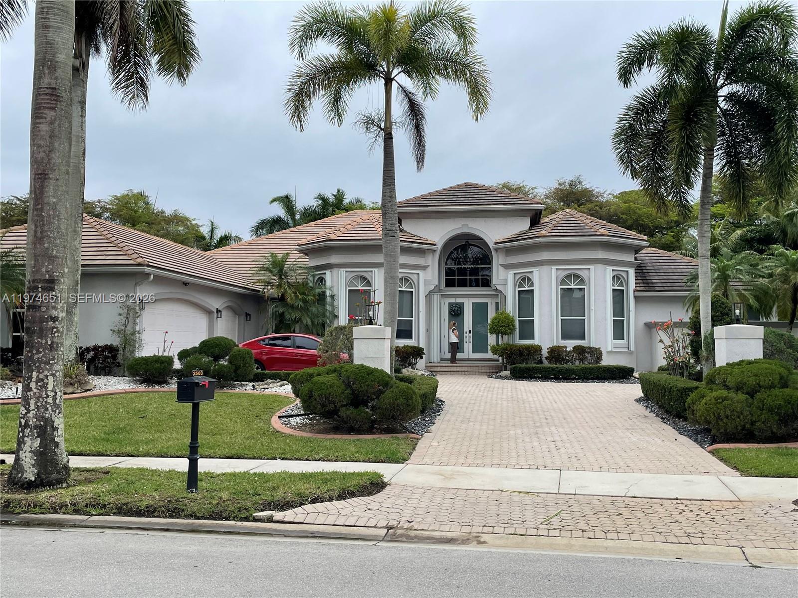 A single-story house with a tiled roof, arched windows, and a paved driveway — 2503 Provence Cir, Weston FL 33327, WESTON, FL