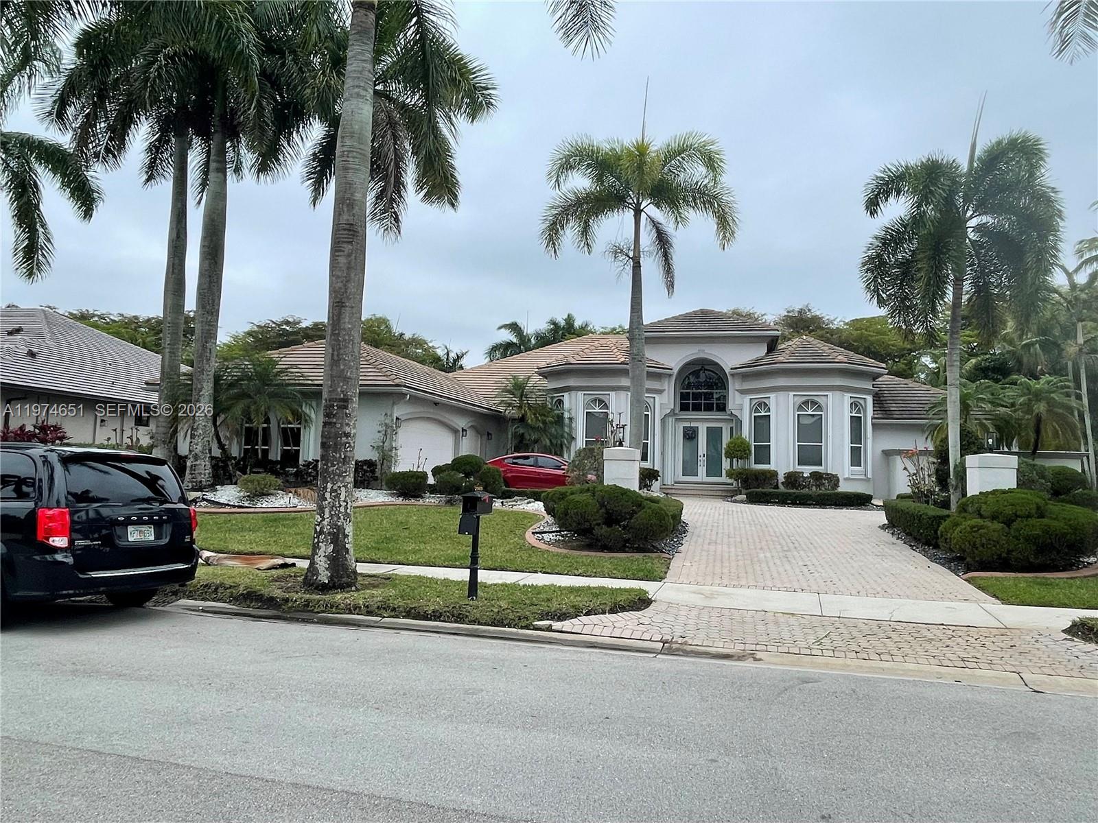 A single-story house with a paved driveway, palm trees, and a black SUV parked outside — 2503 Provence Cir, Weston FL 33327, WESTON, FL