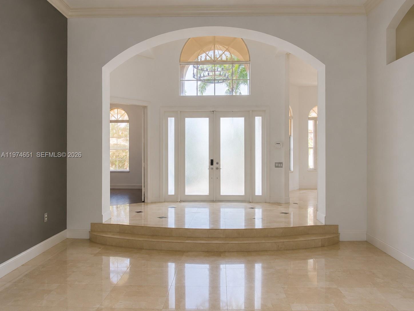 A bright foyer features a raised marble platform, double glass doors, and arched windows — 2503 Provence Cir, Weston FL 33327, WESTON, FL
