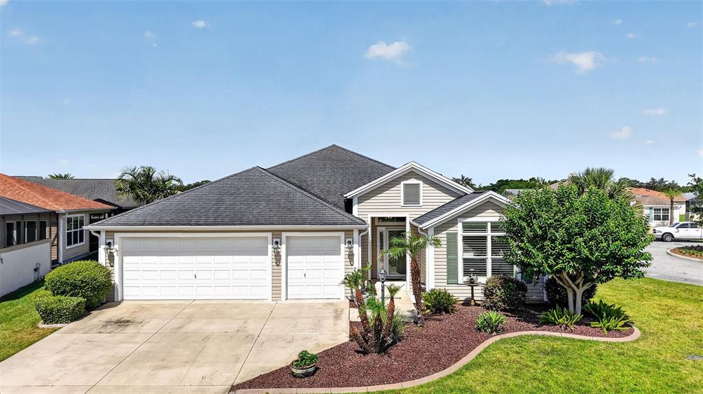 A beige single-story house features a three-car garage and a landscaped front yard — 3746 NEW MOON AVENUE, THE VILLAGES, FL
