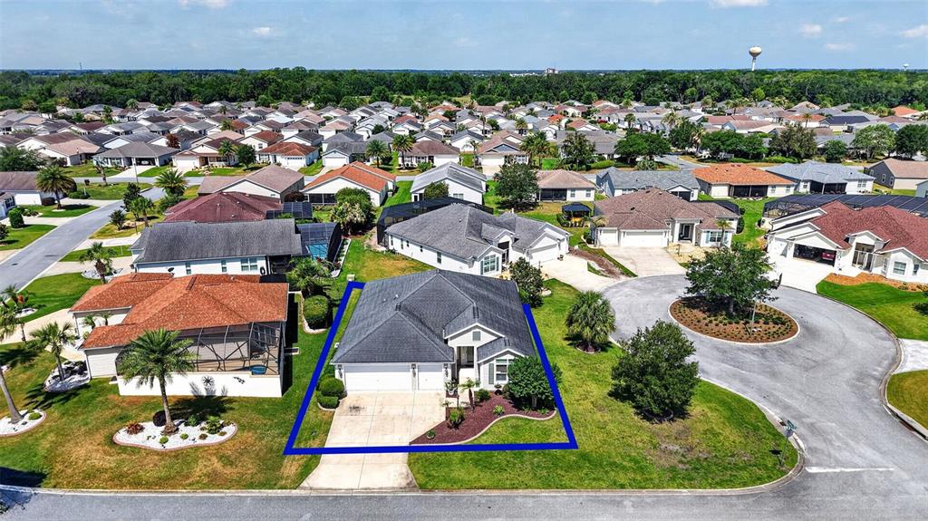 An aerial view shows a single-story house with a dark roof and a paved driveway — 3746 NEW MOON AVENUE, THE VILLAGES, FL