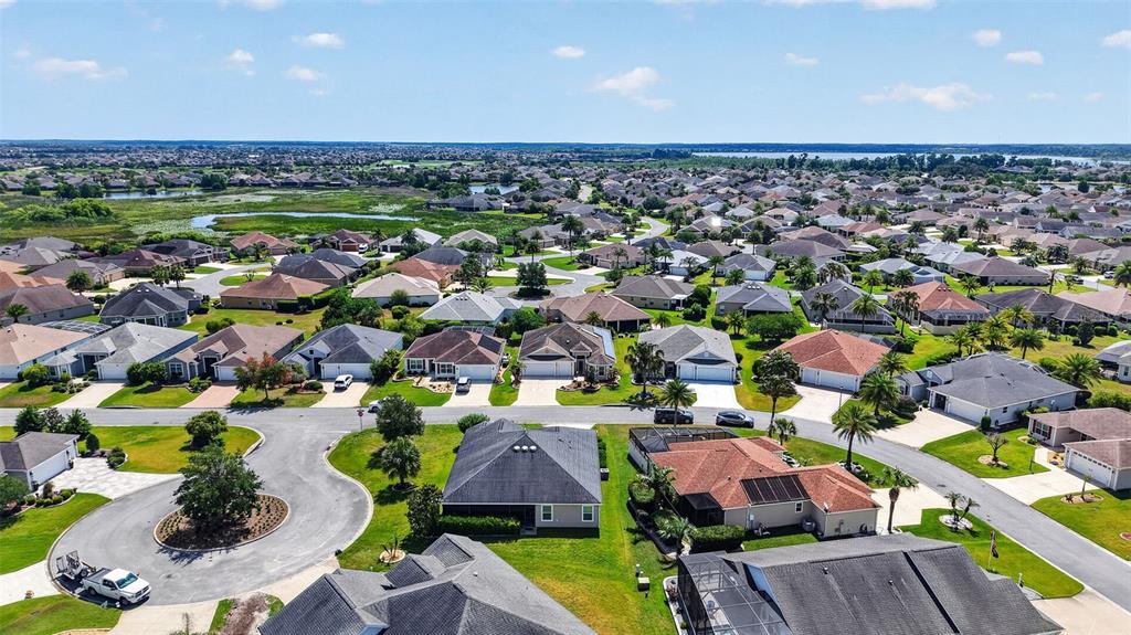 An aerial view shows a suburban neighborhood with numerous single-family homes and paved streets — 3746 NEW MOON AVENUE, THE VILLAGES, FL