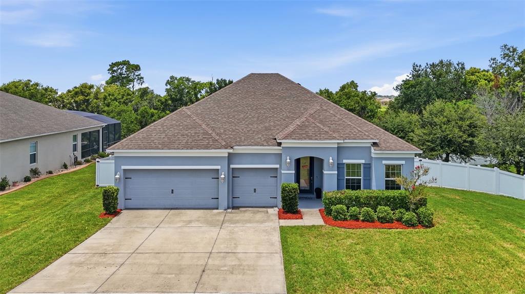 A blue single-story house with a three-car garage and a concrete driveway — 1948 BELL CREEK LOOP, FRUITLAND PARK, FL
