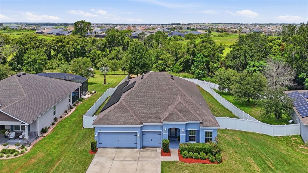 An aerial view of a blue single-story house with a garage and a fenced backyard — 1948 BELL CREEK LOOP, FRUITLAND PARK, FL