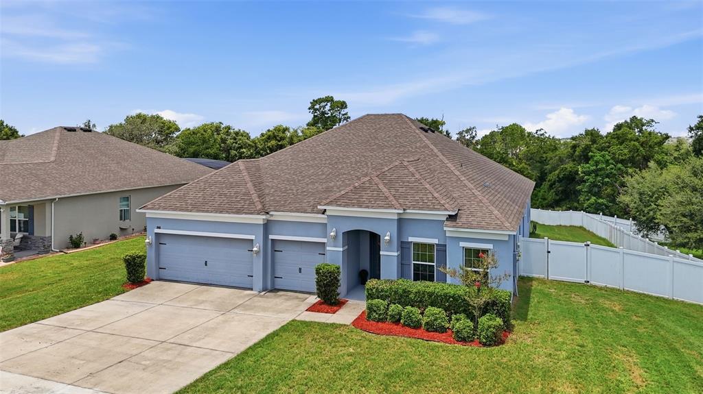 An aerial view of a blue single-story house with a two-car garage and lawn — 1948 BELL CREEK LOOP, FRUITLAND PARK, FL