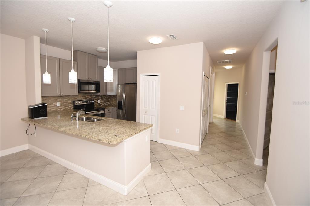 A kitchen with granite countertops, gray cabinets, stainless steel appliances, and tile flooring — 43 LLOYD TRAIL, PALM COAST, FL