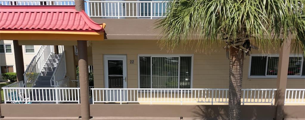 An exterior view of a building with a red roof, white railings, and unit number 22 — 2402 ECUADORIAN WAY UNIT 22, CLEARWATER, FL
