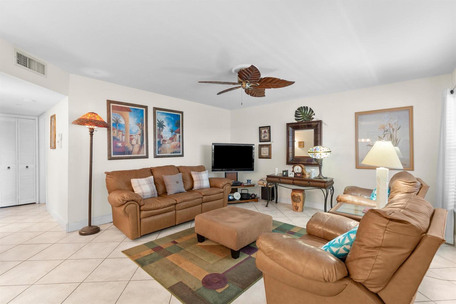 A living room features tan leather furniture, a patterned area rug, and a ceiling fan — 100 SE 6th Avenue # 304, Pompano Beach FL 33060, POMPANO BEACH, FL