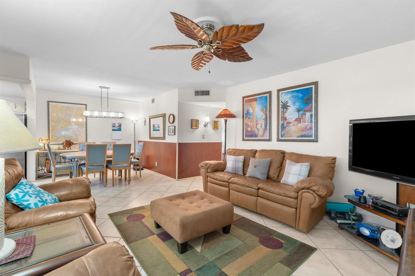 A living room and dining area with tile floors, a leaf-shaped ceiling fan, and furniture — 100 SE 6th Avenue # 304, Pompano Beach FL 33060, POMPANO BEACH, FL