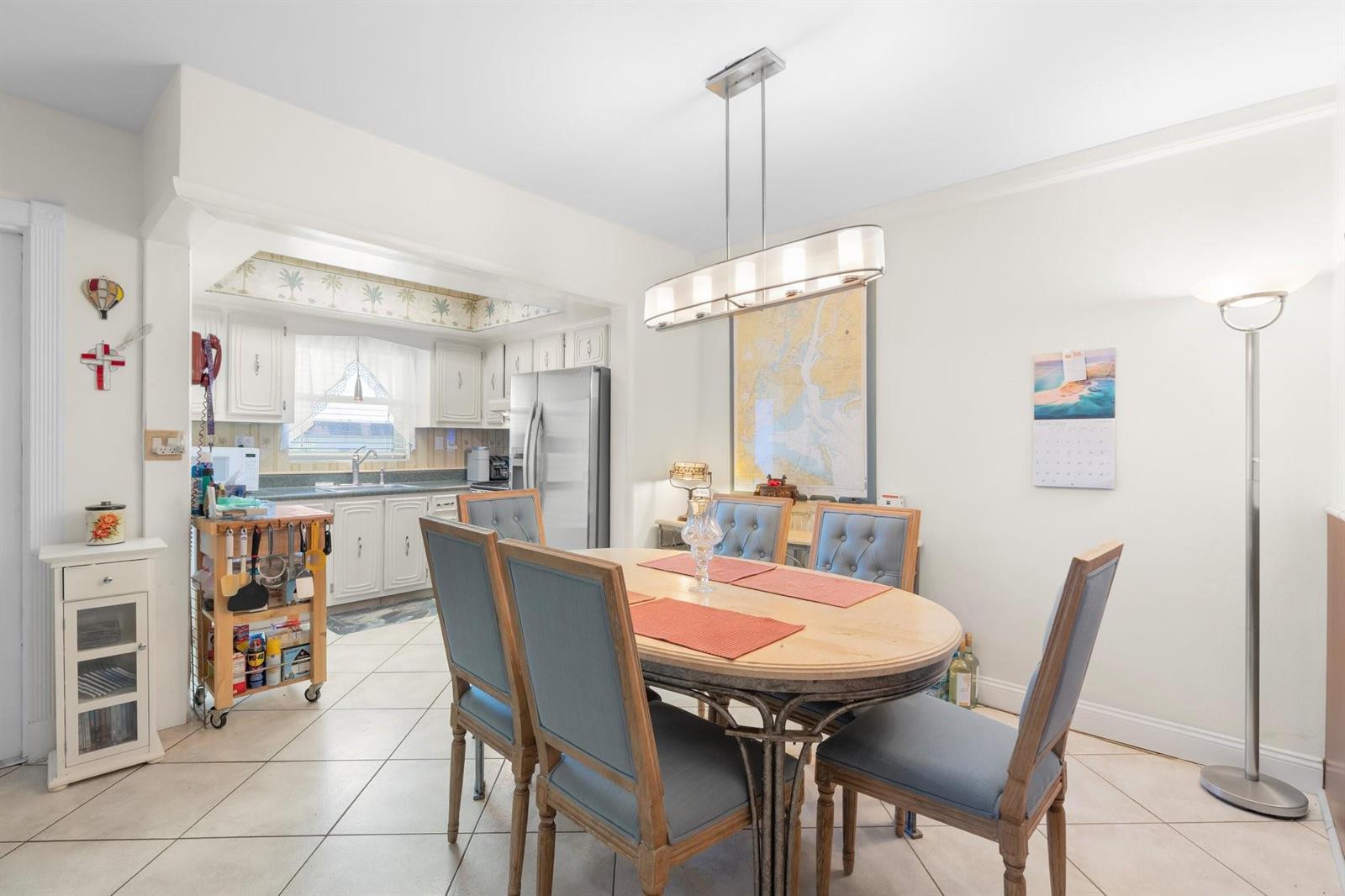 A dining area with a wooden table and blue chairs sits adjacent to a kitchen — 100 SE 6th Avenue # 304, Pompano Beach FL 33060, POMPANO BEACH, FL