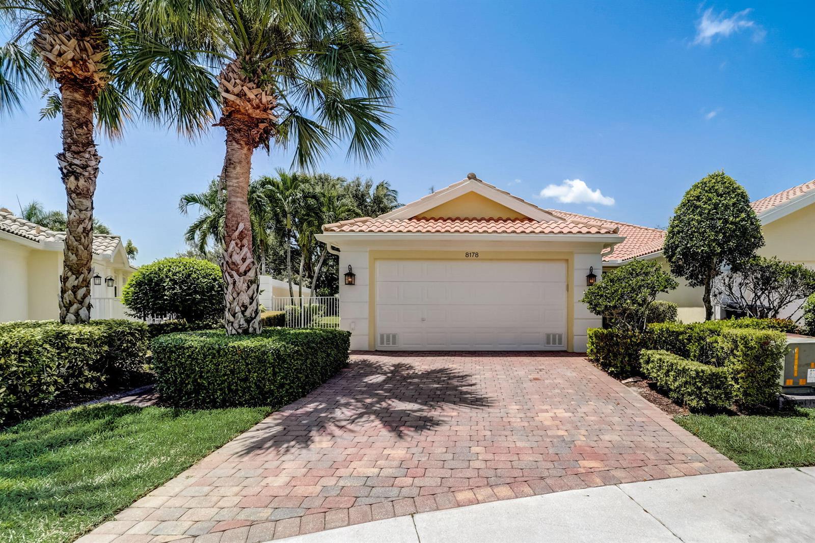 A single-story house with a white garage door, tile roof, and a brick paver driveway — 8178 Montserrat Place, Wellington FL 33414, WELLINGTON, FL