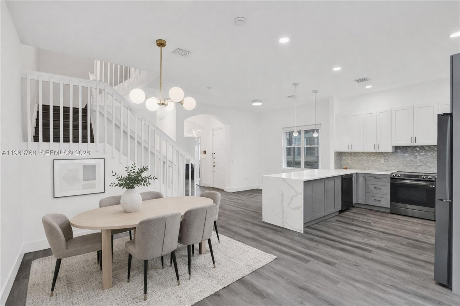 An open-concept kitchen and dining area features white cabinets, a marble-topped island, and stairs — 4253 SW 124th Ter, Miramar FL 33027, MIRAMAR, FL
