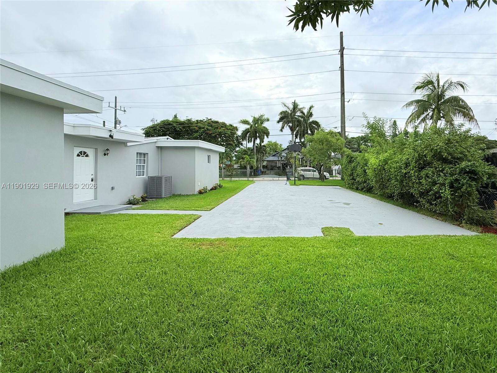 An open-concept living and dining area features white cabinetry, a sectional sofa, and wood furniture — 4340 SW 19th St, West Park FL 33023, WEST PARK, FL