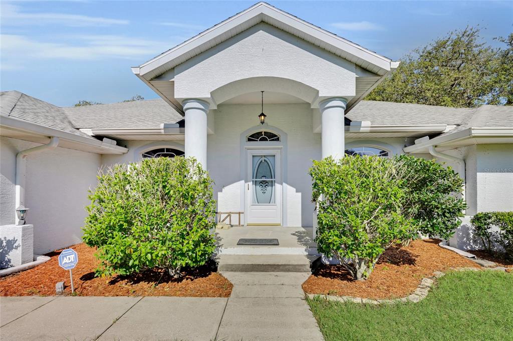 A white house exterior features a covered entryway with two columns and a glass door — 5260 SW 176TH AVENUE, DUNNELLON, FL