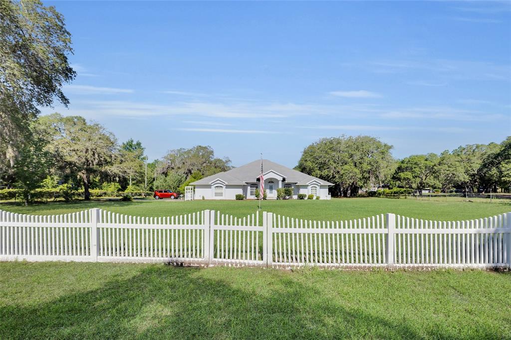 A single-story house with a white picket fence sits on a large, grassy lawn — 5260 SW 176TH AVENUE, DUNNELLON, FL