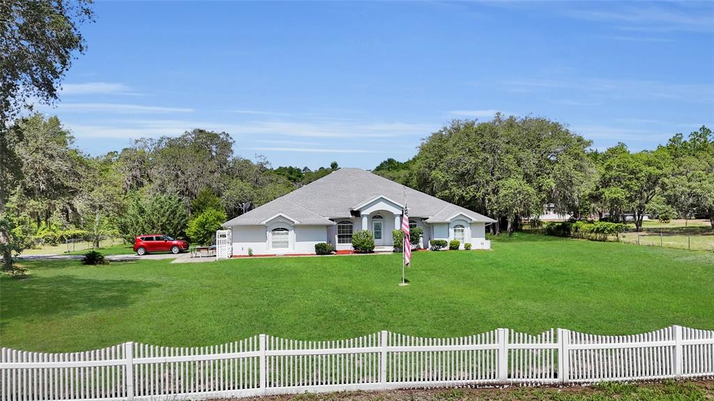 A single-story house with a white exterior and a gray roof sits on a lawn — 5260 SW 176TH AVENUE, DUNNELLON, FL