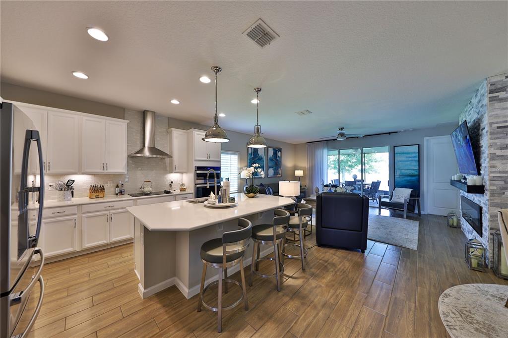 A kitchen with white cabinets and a large island opens into a living area — 1049 WANDERER DRIVE, DELTONA, FL