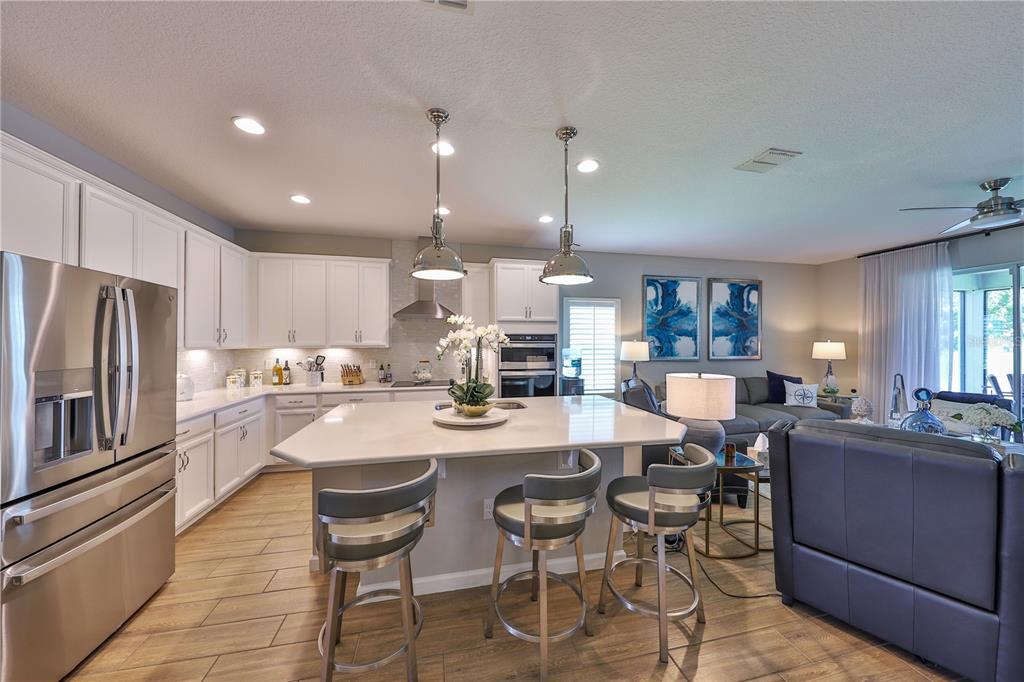 A modern kitchen with white cabinets, a large island, and stainless steel appliances — 1049 WANDERER DRIVE, DELTONA, FL