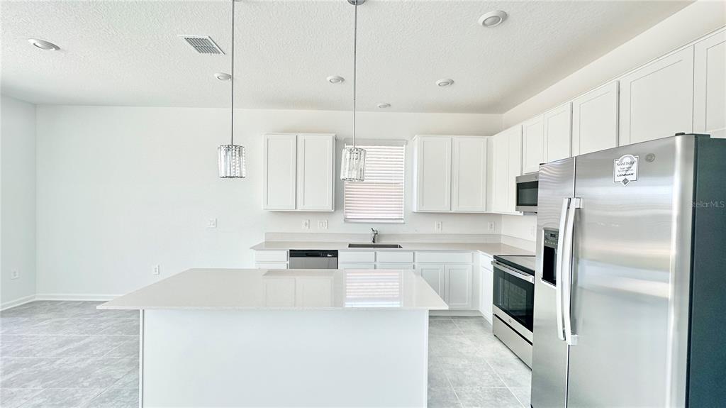 A modern kitchen features white cabinets, stainless steel appliances, and a central island — 683 DARING DRIVE, DAVENPORT, FL