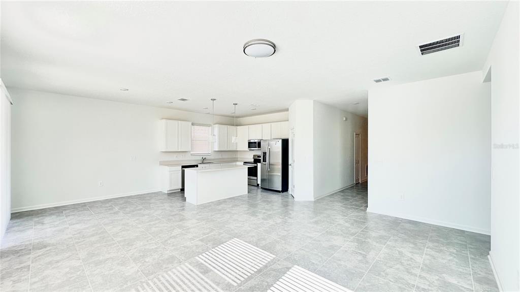 An open-concept kitchen with white cabinets, stainless steel appliances, and a central island — 683 DARING DRIVE, DAVENPORT, FL