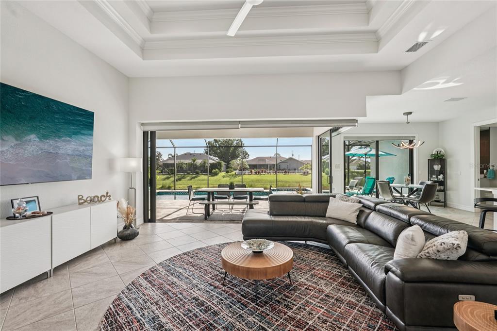 A living room with a large sectional sofa, circular rug, and sliding doors opening to a pool — 35 MEDALIST COURT, ROTONDA WEST, FL