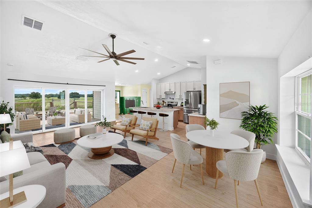 An open-concept living and dining area features light wood floors, a kitchen island, and patio doors — 10240 NW 7TH TERRACE, BRANFORD, FL
