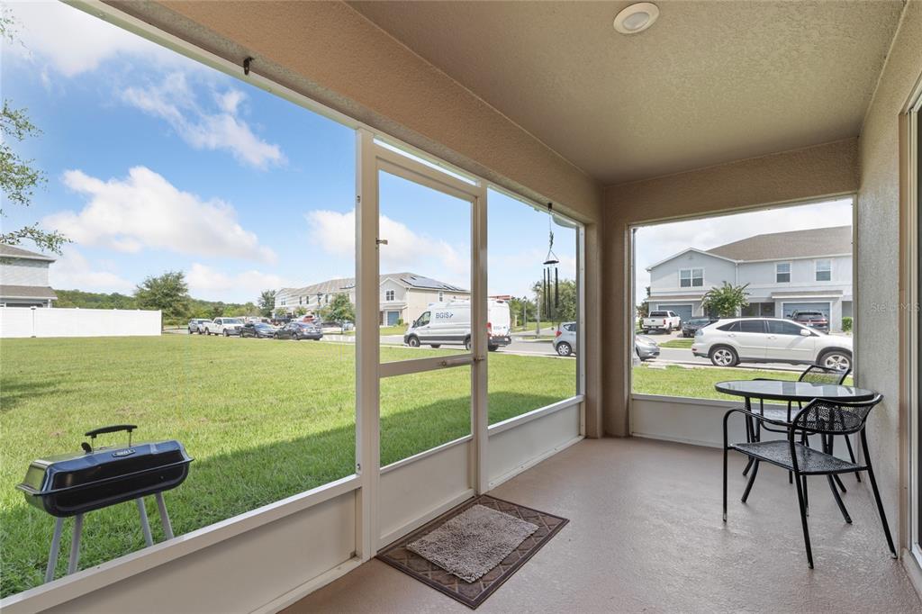 A screened-in patio features a grill, a small dining set, and views of a neighborhood — 3075 FIELDWOOD CIRCLE, ST CLOUD, FL