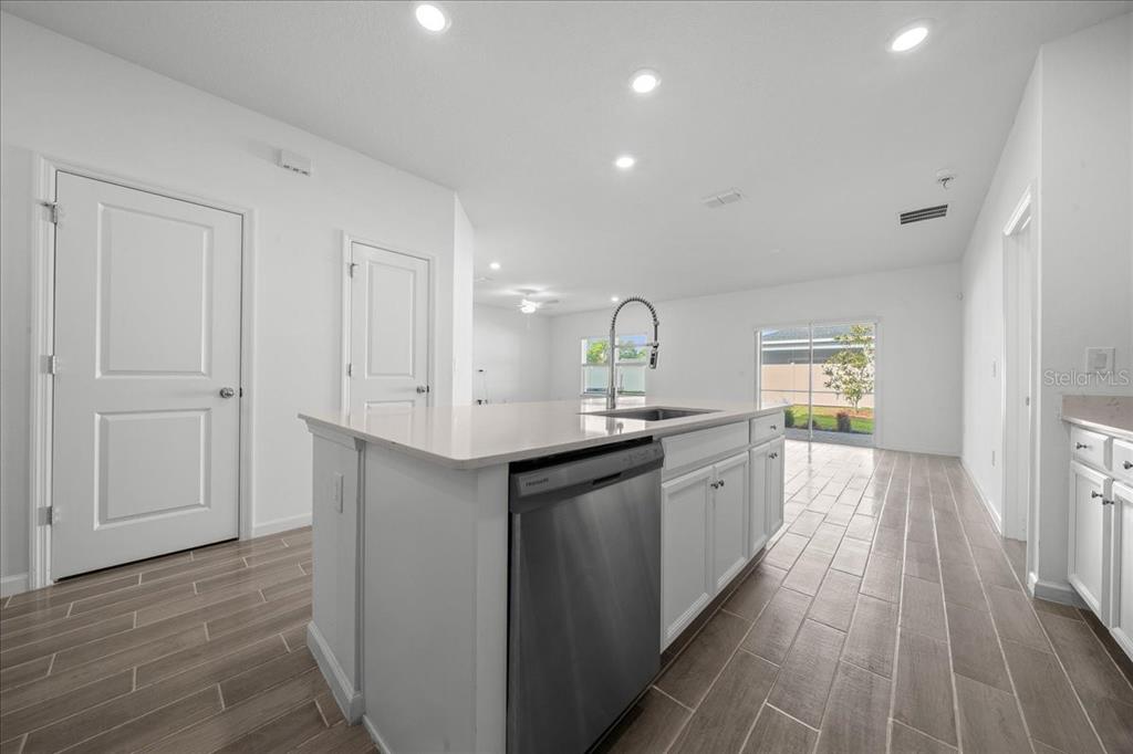 A kitchen with a central island, stainless steel dishwasher, white cabinets, and wood-look tile flooring — 7542 SW 76TH TERRACE, OCALA, FL
