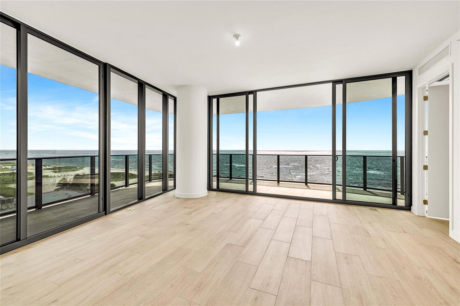 An empty room with light wood-look flooring and floor-to-ceiling windows overlooking the ocean — 900 N Ocean Boulevard # 606, Pompano Beach FL 33062, POMPANO BEACH, FL