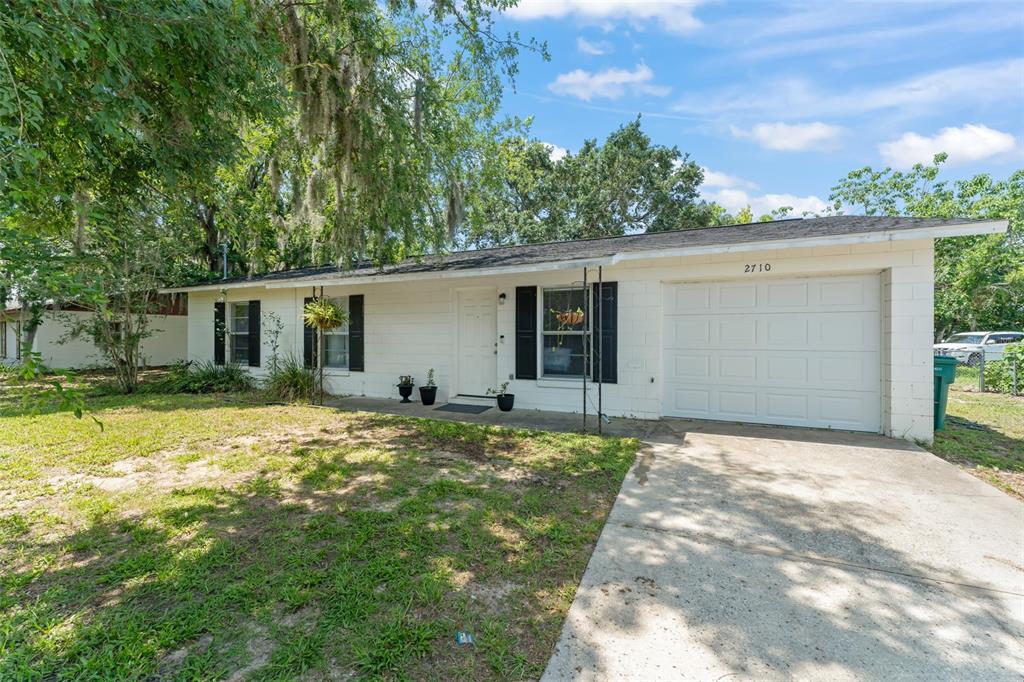 A single-story white house with a concrete driveway and a one-car garage — 2710 W COUNTY ROAD 44, EUSTIS, FL