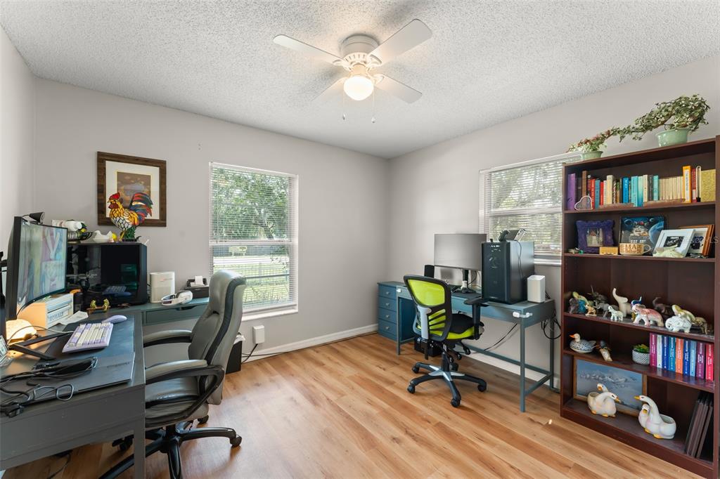 A home office features two desks, two chairs, a bookshelf, and light wood-look flooring — 2710 W COUNTY ROAD 44, EUSTIS, FL