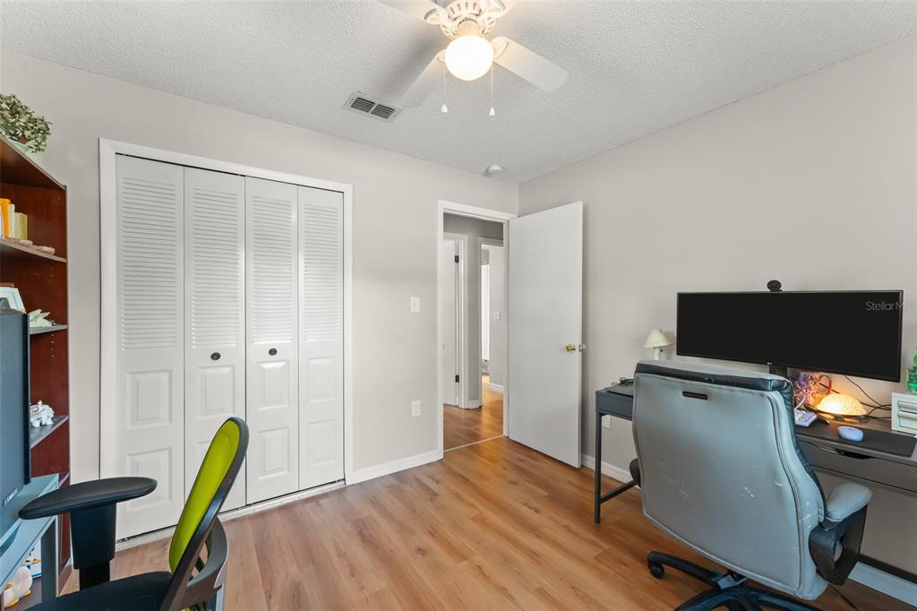 A home office with wood-look flooring, a ceiling fan, a closet, and a desk setup — 2710 W COUNTY ROAD 44, EUSTIS, FL