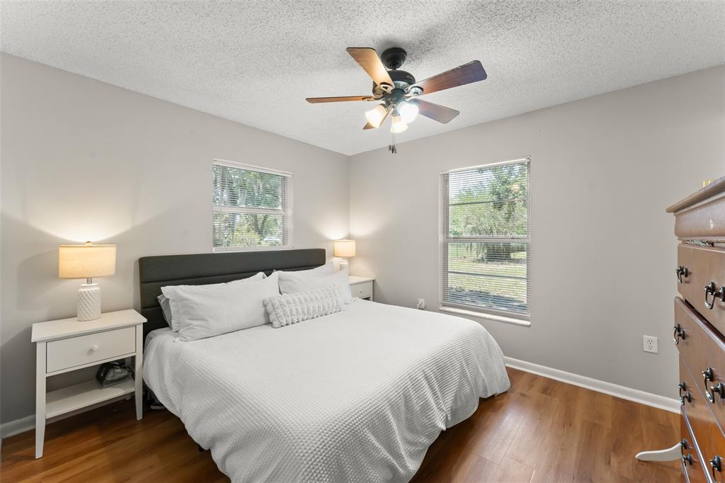A bedroom features a bed with a dark headboard, two nightstands, and wood-look flooring — 2710 W COUNTY ROAD 44, EUSTIS, FL
