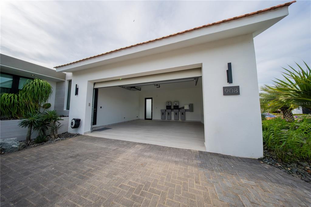 A modern house exterior features a paved driveway, a covered entryway, and tiered stone planters — 1 CORREDOR MIRALAGO UNIT 908, DORADO, PR