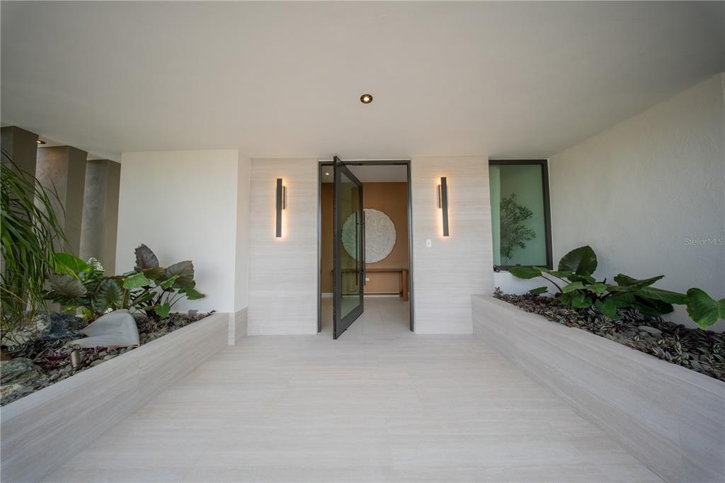 An open garage with light-colored flooring, a paved driveway, and modern white exterior walls — 1 CORREDOR MIRALAGO UNIT 908, DORADO, PR