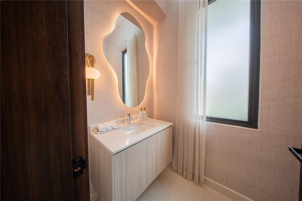 A modern entryway features a glass door, stone-tiled floors, wall sconces, and two built-in planters — 1 CORREDOR MIRALAGO UNIT 908, DORADO, PR