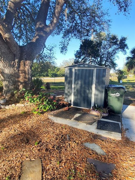 A metal storage shed sits on a concrete pad next to a large tree — 6880 PLEASANT COURT, NORTH PORT, FL