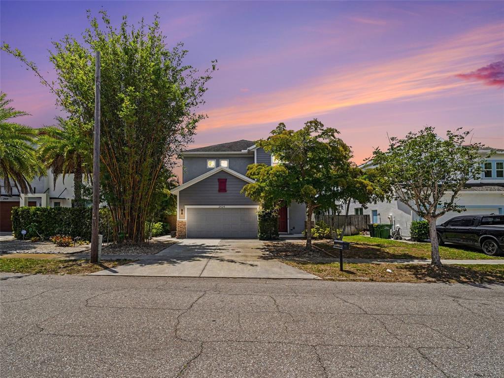 A two-story suburban house with a gray garage and a driveway faces a paved street — 2424 WOOD STREET, SARASOTA, FL