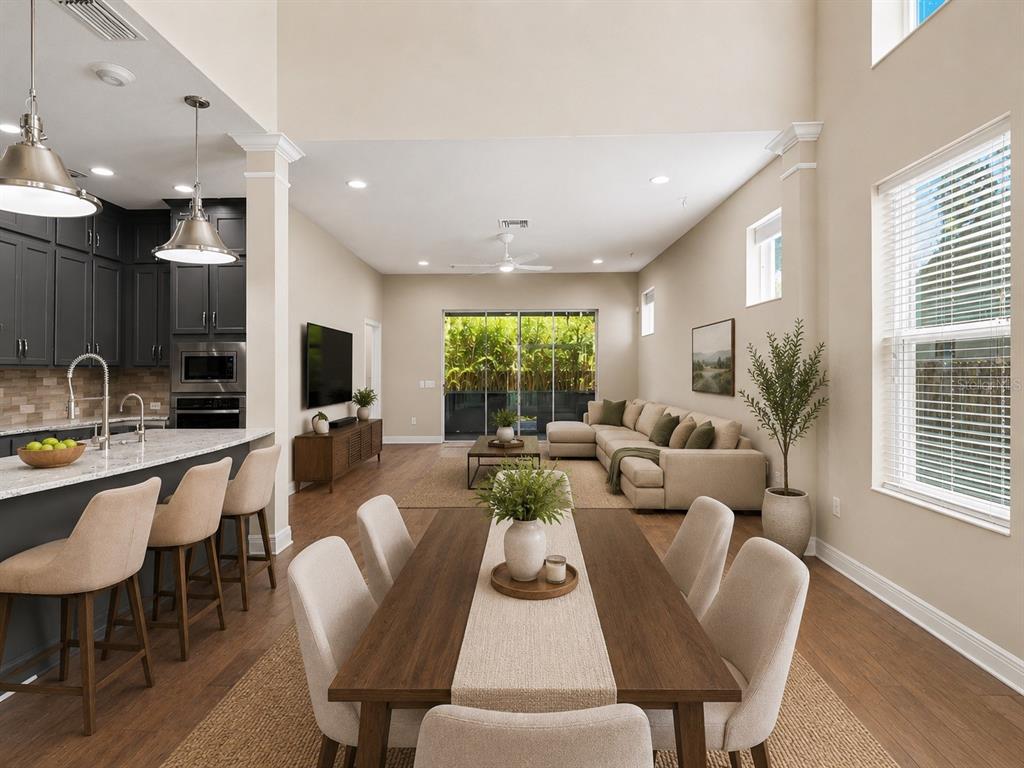 An open-concept living and dining area features a kitchen island, high ceilings, and sliding doors — 2424 WOOD STREET, SARASOTA, FL