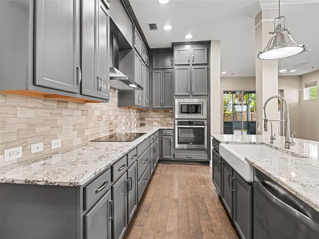 A kitchen features gray cabinets, granite countertops, a farmhouse sink, and stainless steel appliances — 2424 WOOD STREET, SARASOTA, FL