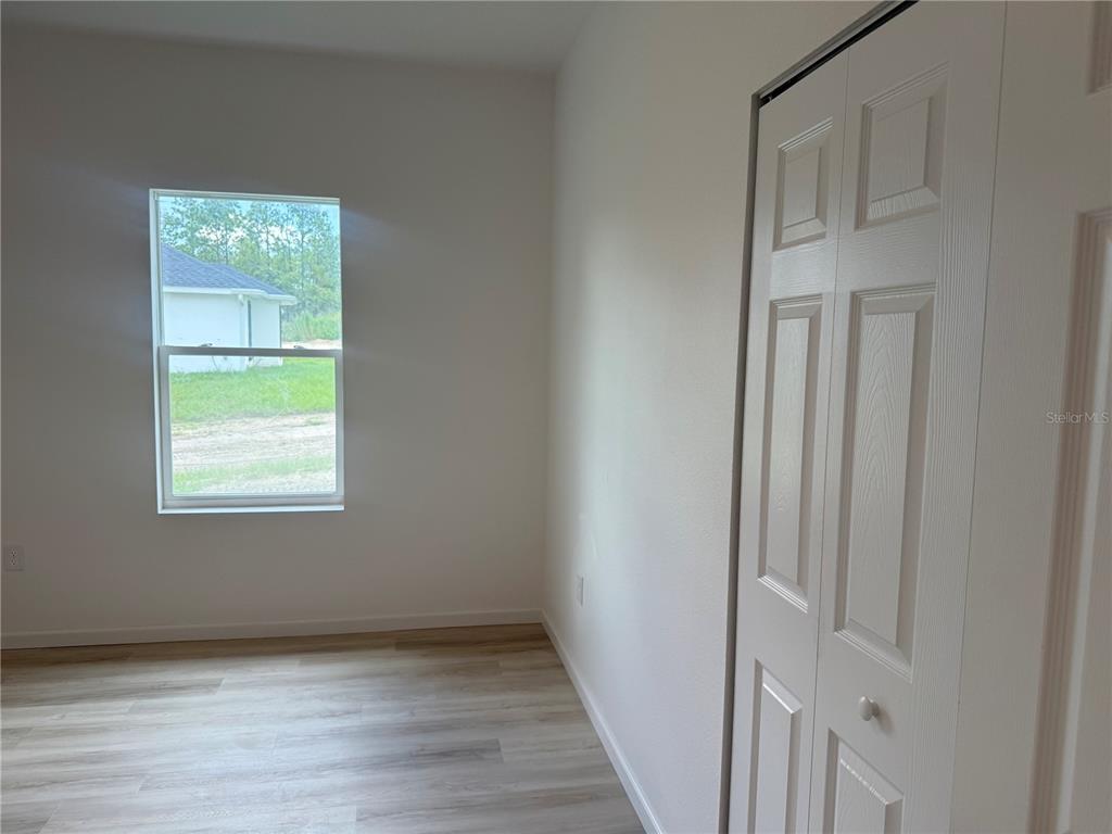 An open-concept living area features light wood-look flooring, a ceiling fan, and a front door — 12854 SW 84TH TERRACE ROAD, OCALA, FL