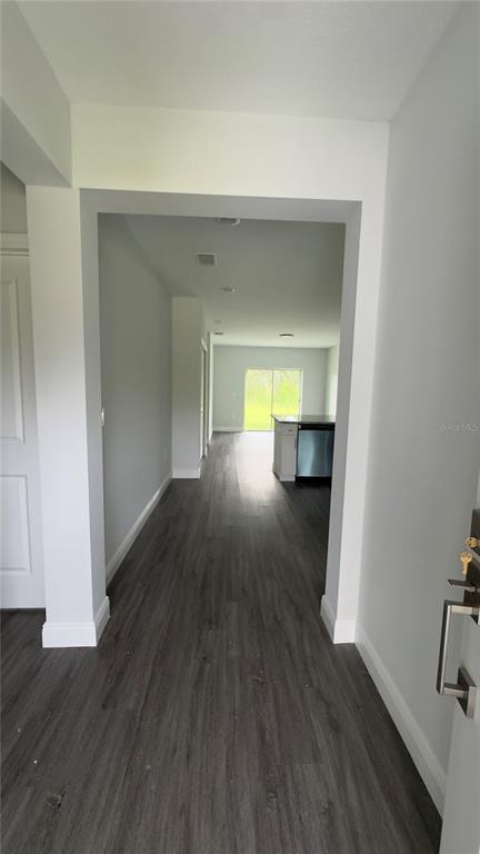 A view from an entryway looking down a hallway toward a kitchen and sliding doors — 2217 FRASER STREET, PORT CHARLOTTE, FL