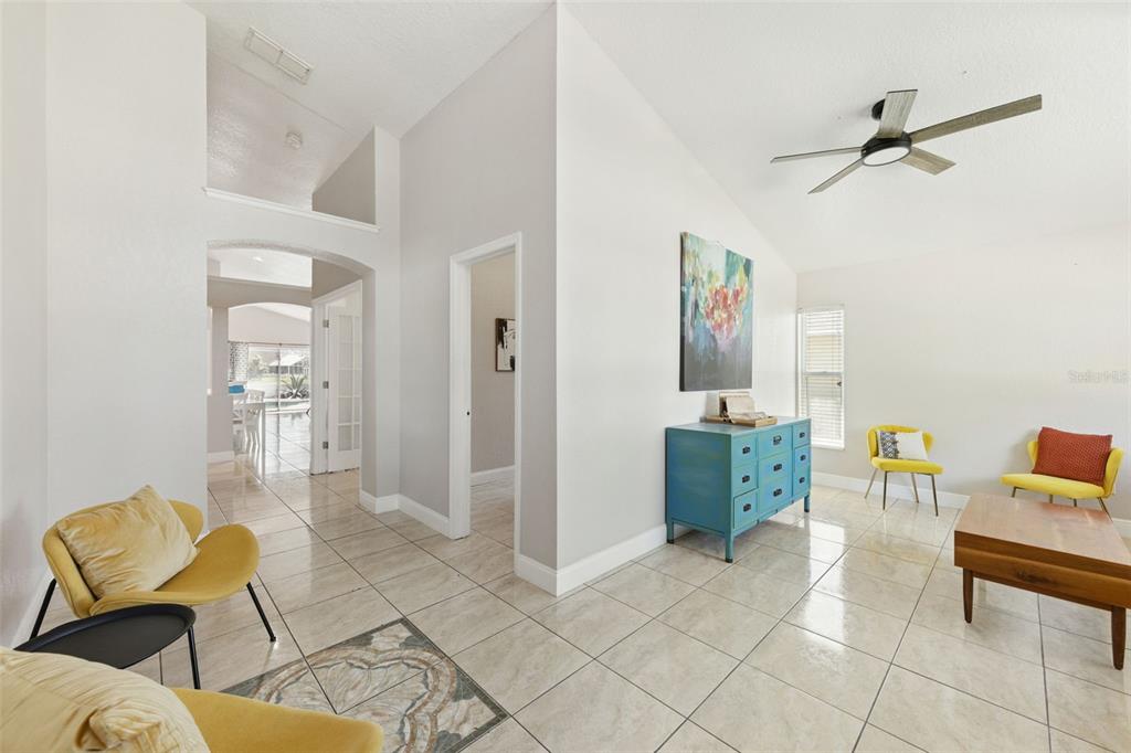 A bright living area features tile flooring, vaulted ceilings, a ceiling fan, and yellow chairs — 7829 ELMSTONE CIRCLE, ORLANDO, FL