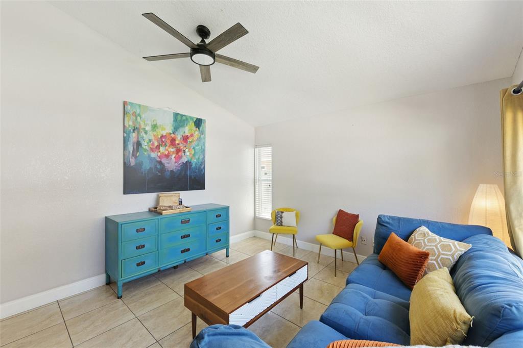 A living room features a blue sofa, a wooden coffee table, and a teal dresser — 7829 ELMSTONE CIRCLE, ORLANDO, FL