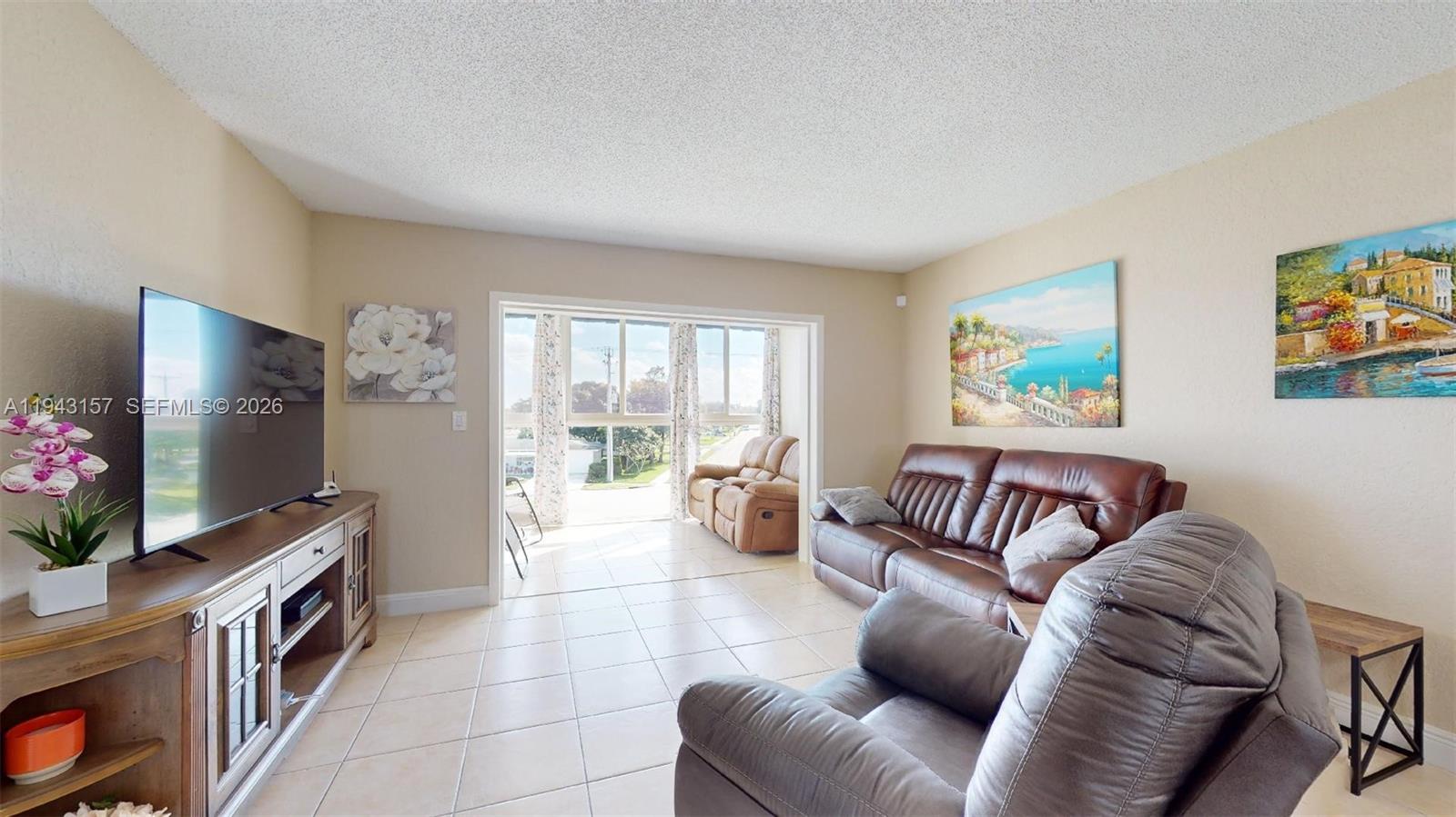 A living room features tile flooring, a leather sofa, a recliner, and a television console — 7877 Golf Cir Dr # 304, Margate FL 33063, MARGATE, FL