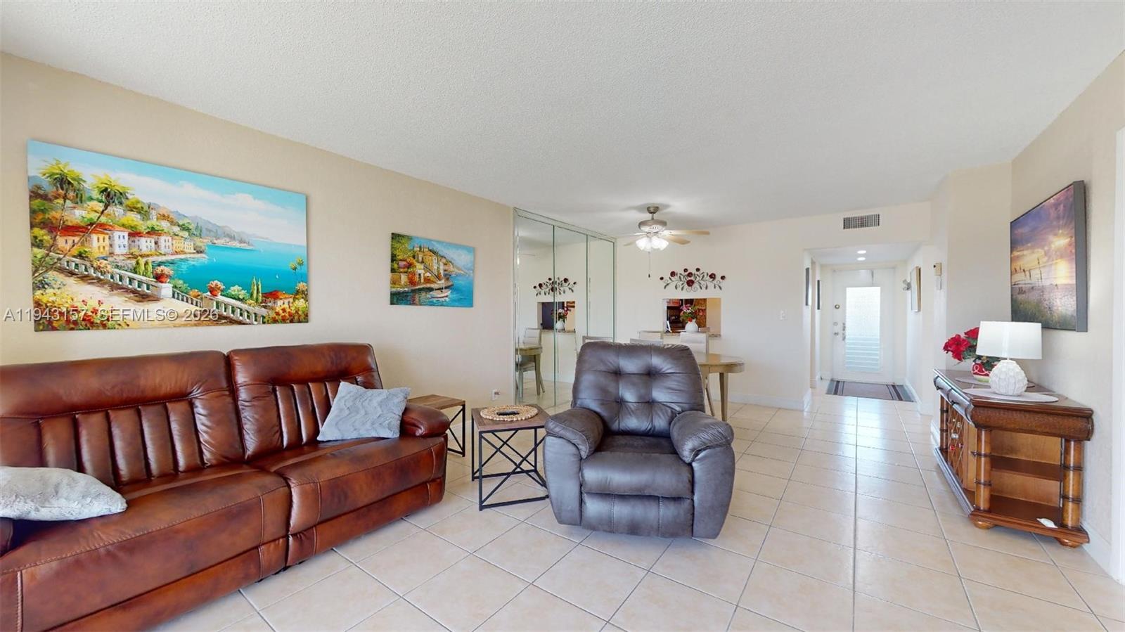 A living room features a leather sofa, a recliner, tile flooring, and a mirrored wall — 7877 Golf Cir Dr # 304, Margate FL 33063, MARGATE, FL