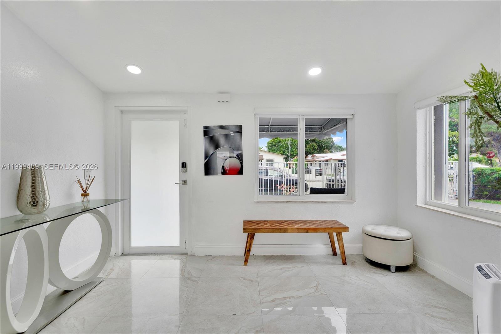 A bright entryway features white walls, tile flooring, a glass console table, and a wooden bench — 4310 SW 7th St, Miami FL 33134, MIAMI, FL