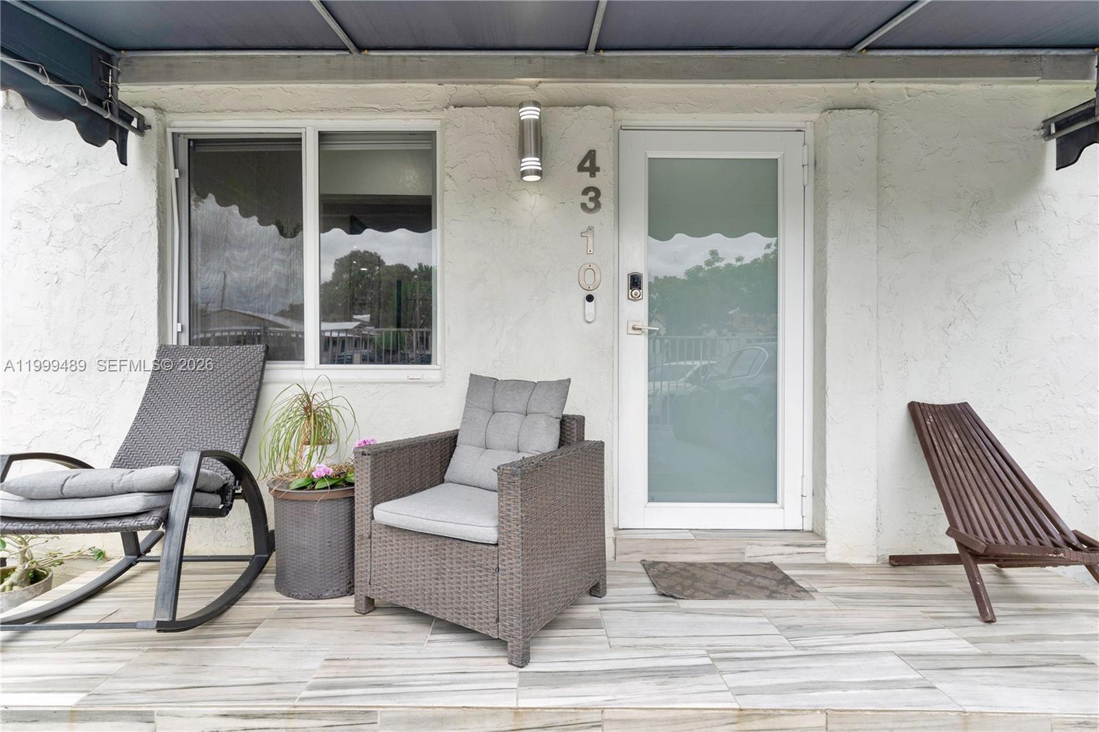 A covered porch features tiled flooring, three chairs, a potted plant, and a front door — 4310 SW 7th St, Miami FL 33134, MIAMI, FL